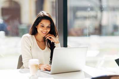 Woman at coffee shop sitting by laptop computer